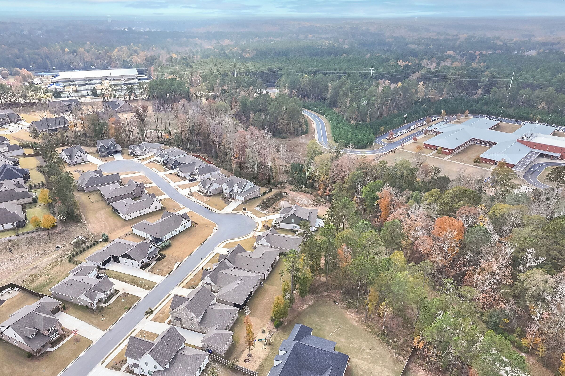 An aerial view of a residential area with houses, roads, and a large building in the background.