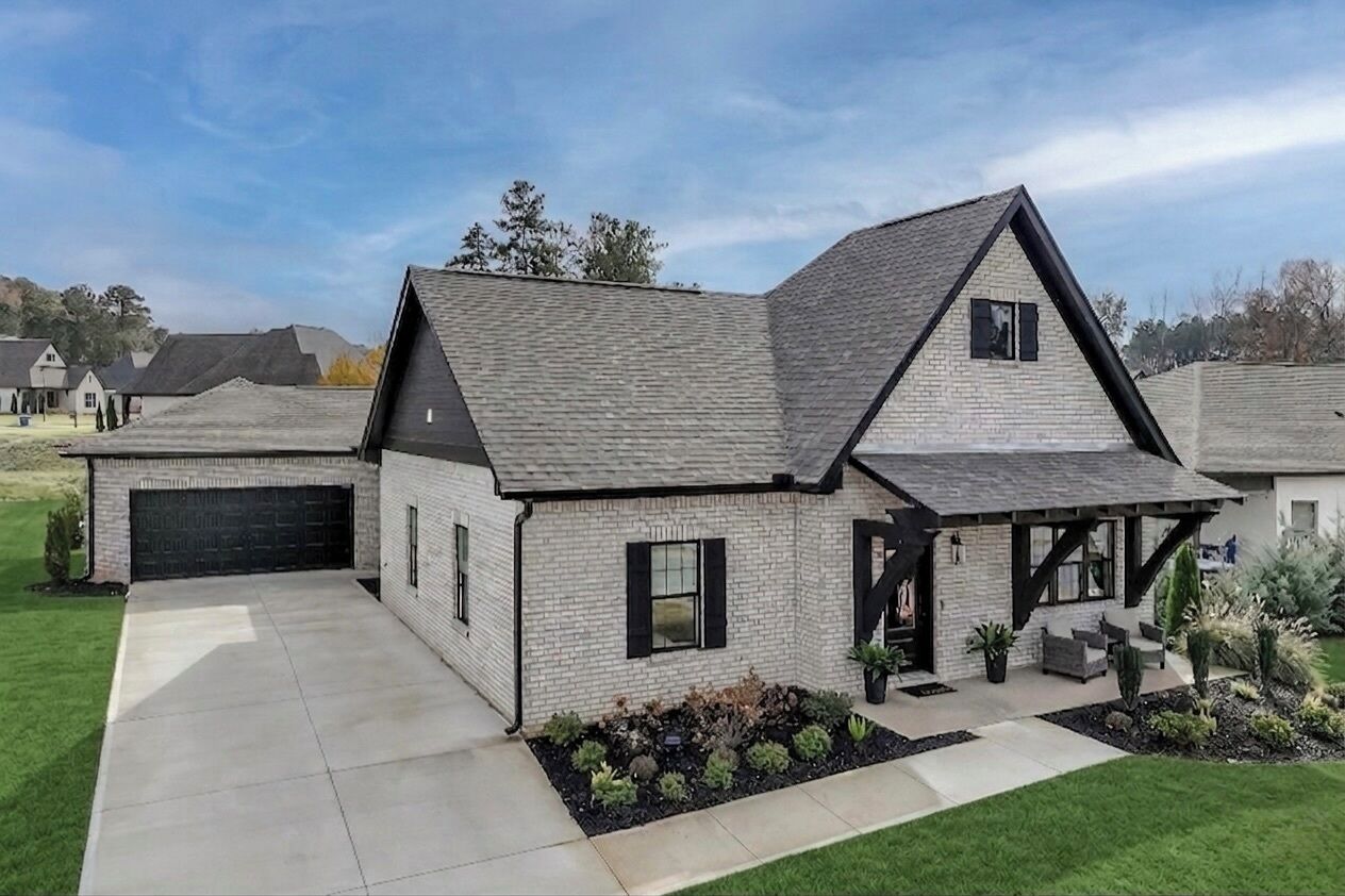 A modern house with a garage, a covered porch, and a landscaped front yard.