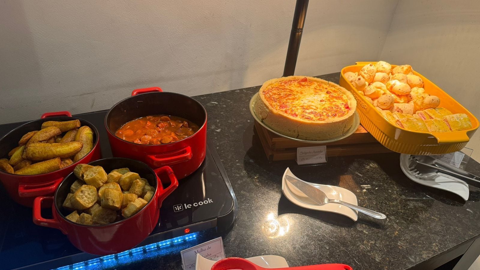 Un bufé con diversos platos, incluyendo opciones fritas, una tarta y un plato de queso.