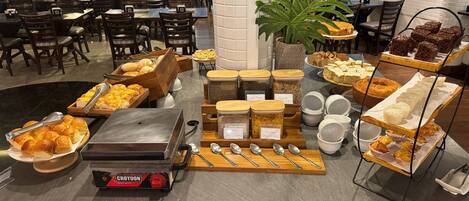 A buffet setup with various food items, serving utensils, and a steam table.