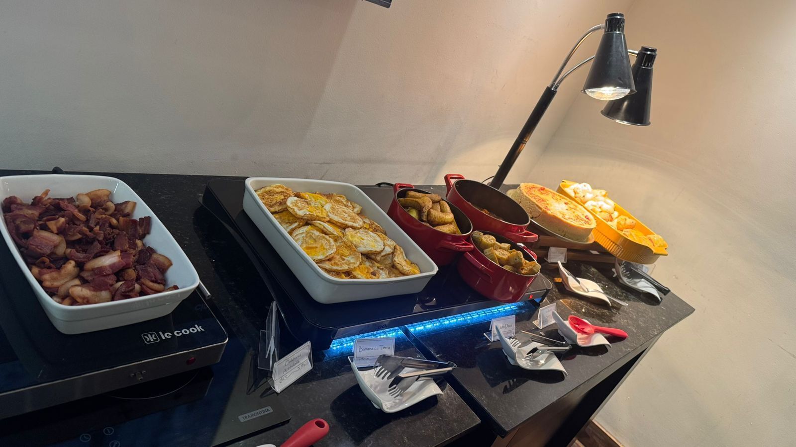 A buffet table with various dishes, a black desk lamp, and a blue light strip.