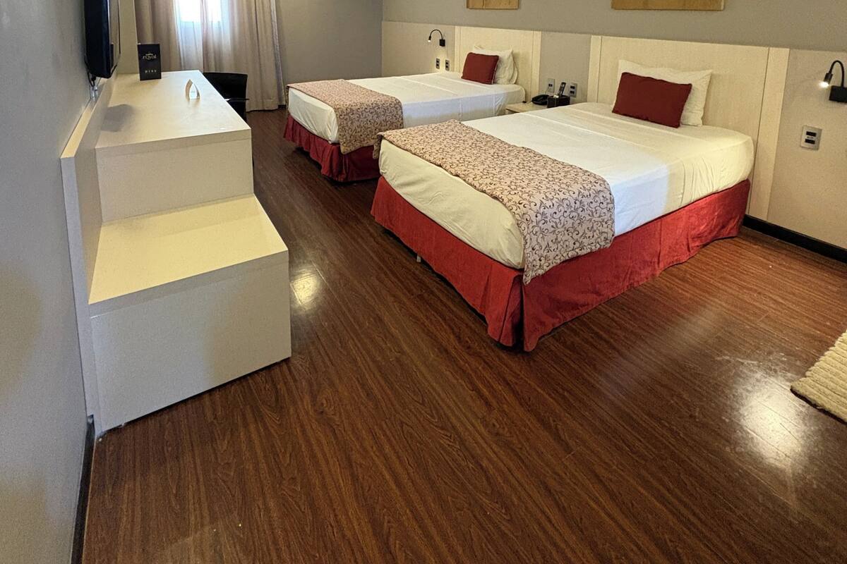 Una habitación de hotel con dos camas, un escritorio y un equipo de aire acondicionado.