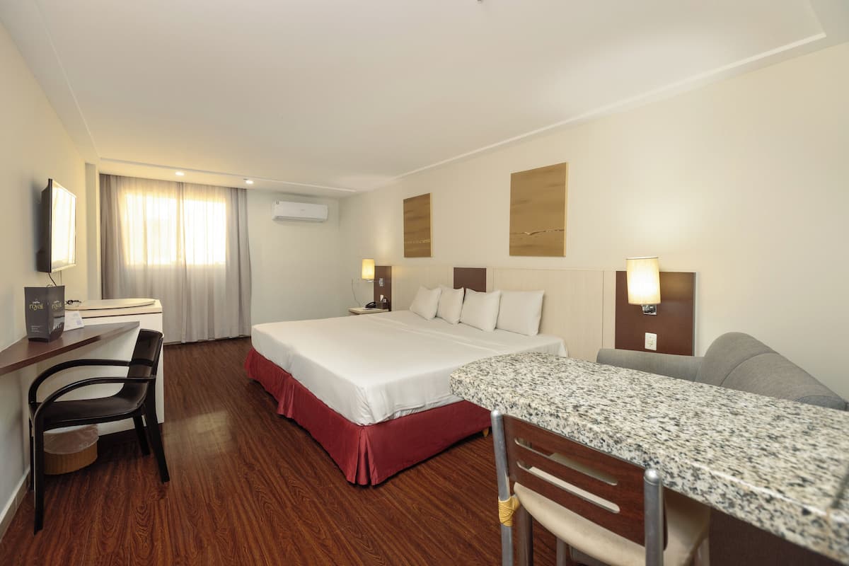 A hotel room with a bed, desk, chair, and a television.