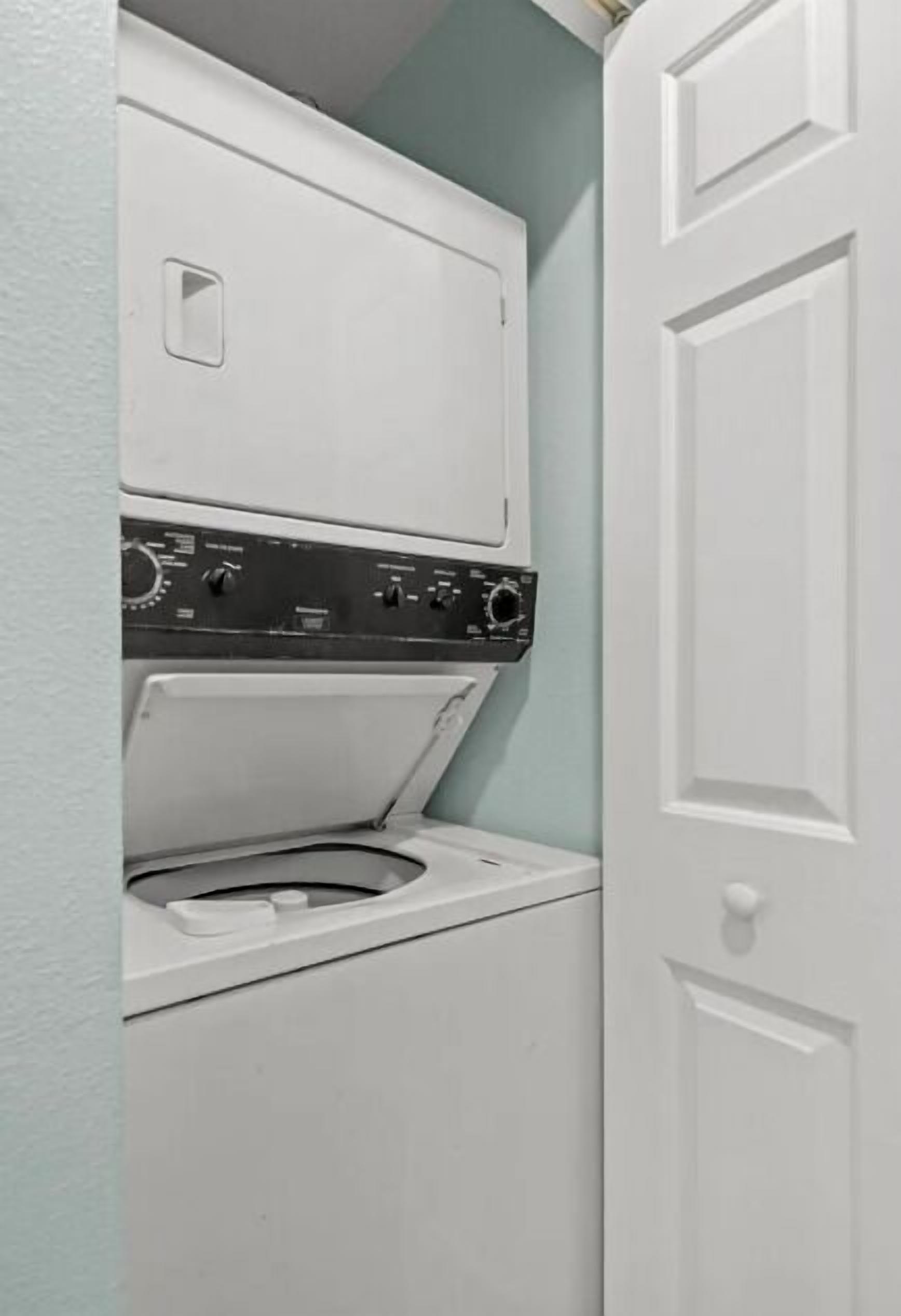 Un appareil compact combinant lave-linge et sèche-linge, installé dans un petit espace buanderie avec une porte simple et des murs de couleur claire.