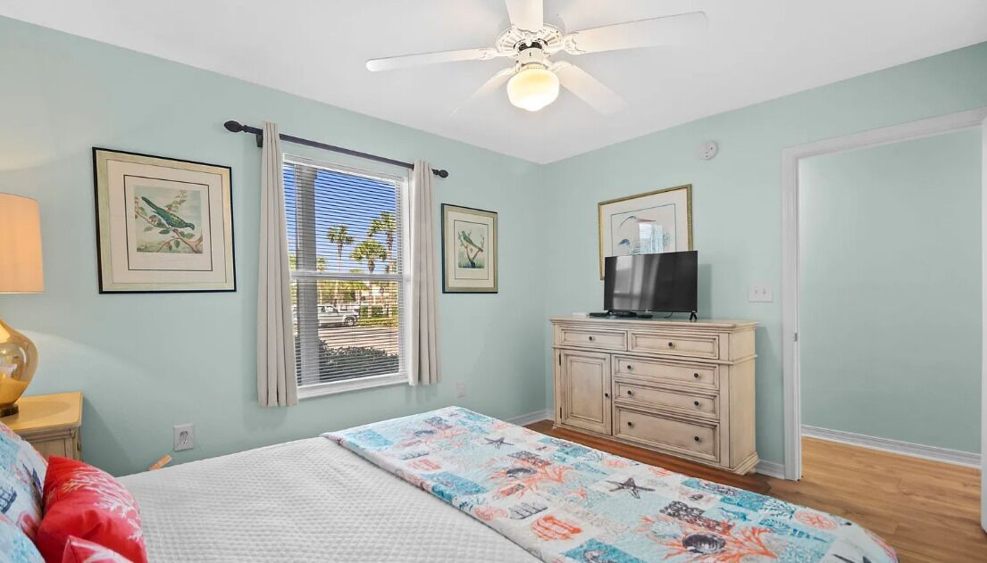 A bedroom with a bed, a dresser, a television, and framed artwork on the walls.