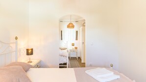 Een slaapkamer met een bed, een bedlamp, een nachtkastje, een dressoir en een spiegel.