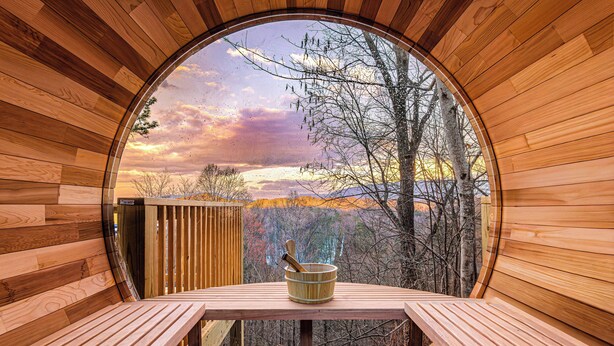 A wooden cabin with a circular window, a wooden bench, and a wooden table with a wooden bowl. - Romantic Mtn Spa Retreat - Views • Hot Tub • Sauna • Fire Pit  • Cold Plunge (Gatlinburg)