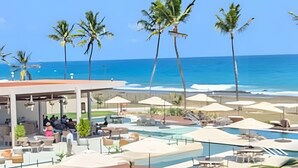 Un complexe hôtelier doté d’une piscine, de parasols de plage et de palmiers.