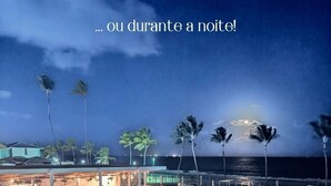Une vue nocturne d’un complexe hôtelier doté de plusieurs piscines, de palmiers et d’une plage en arrière-plan.