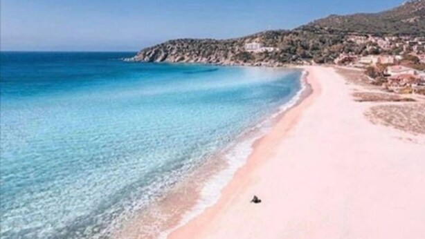 A beach with clear water, a sandy shore, and a person walking. - Villa Terri – Beachfront Retreat on Solanas Beach (Solanas)