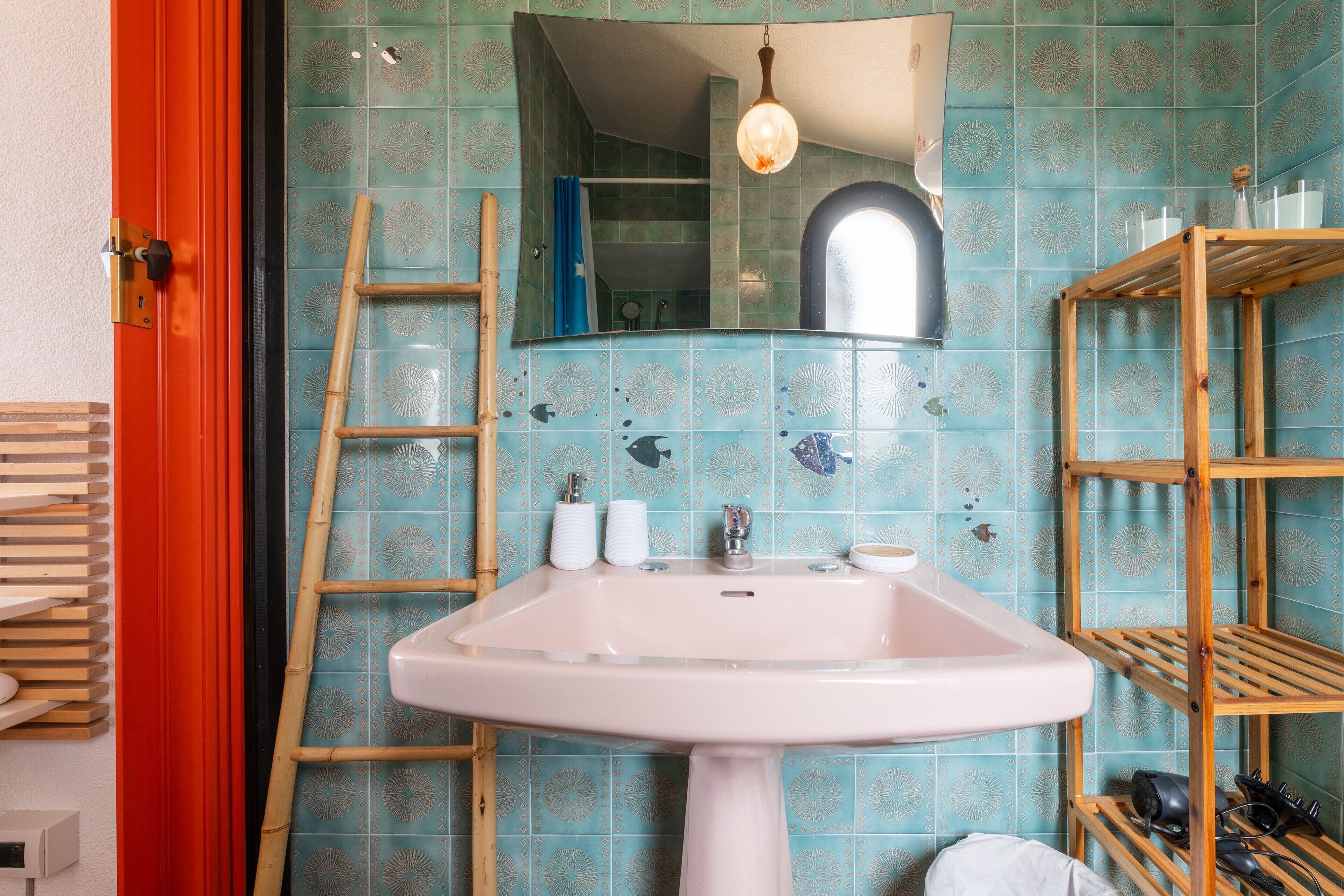 A bathroom with a white sink, a mirror, a wooden ladder, and a shelf with toiletries.