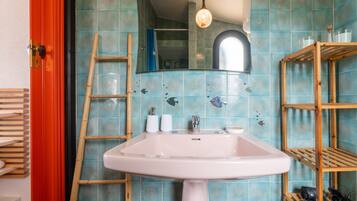 A bathroom with a white sink, a mirror, a wooden ladder, and a shelf with toiletries.