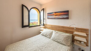 A bedroom with a bed, a window with a view, a painting, and a bedside table. - Villa Terri – Beachfront Retreat on Solanas Beach (Solanas)