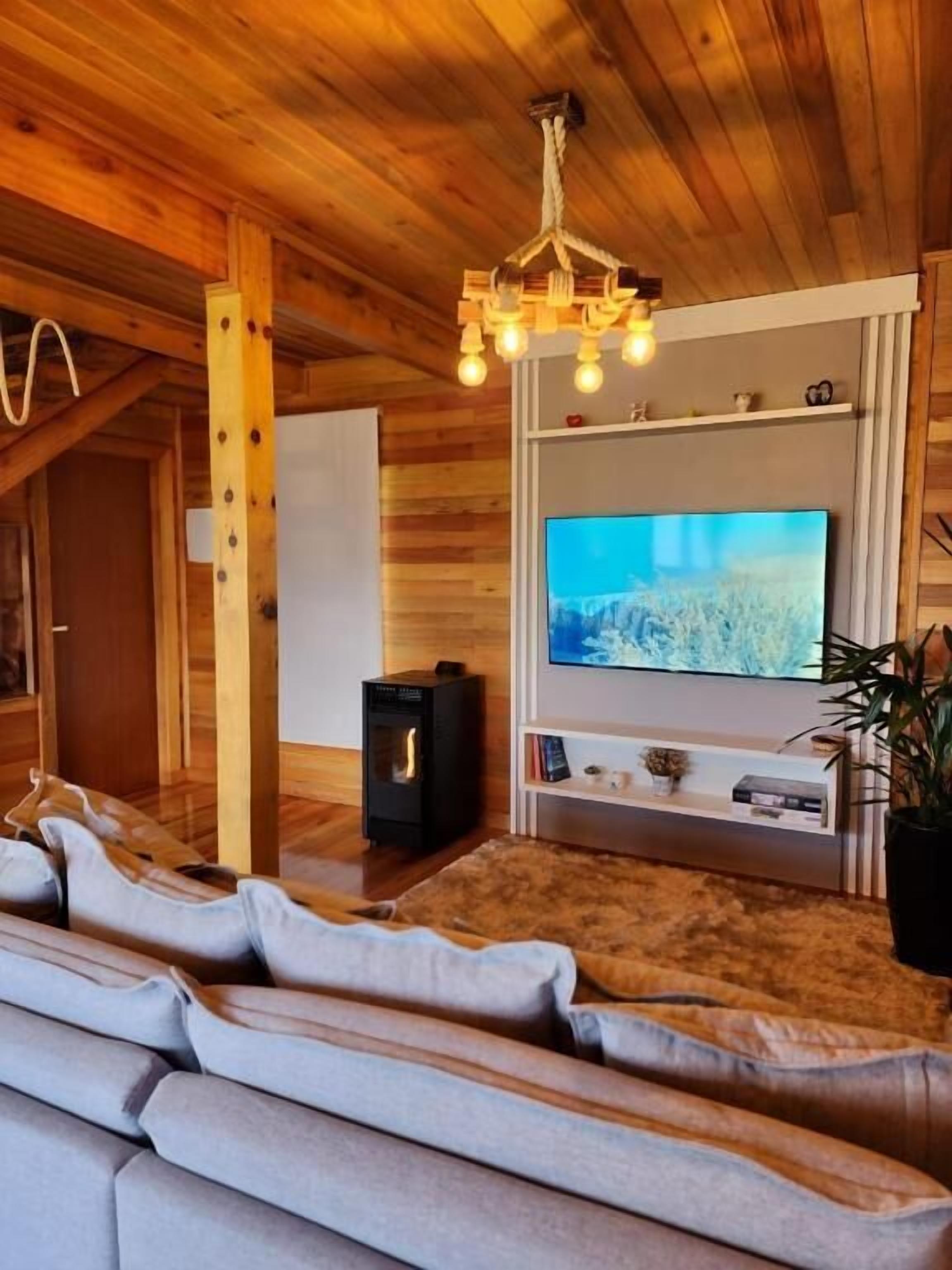 A cozy wooden interior with a sofa, a TV, and a fireplace.