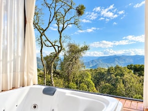 A bathroom with a bathtub and a view of a mountainous landscape.