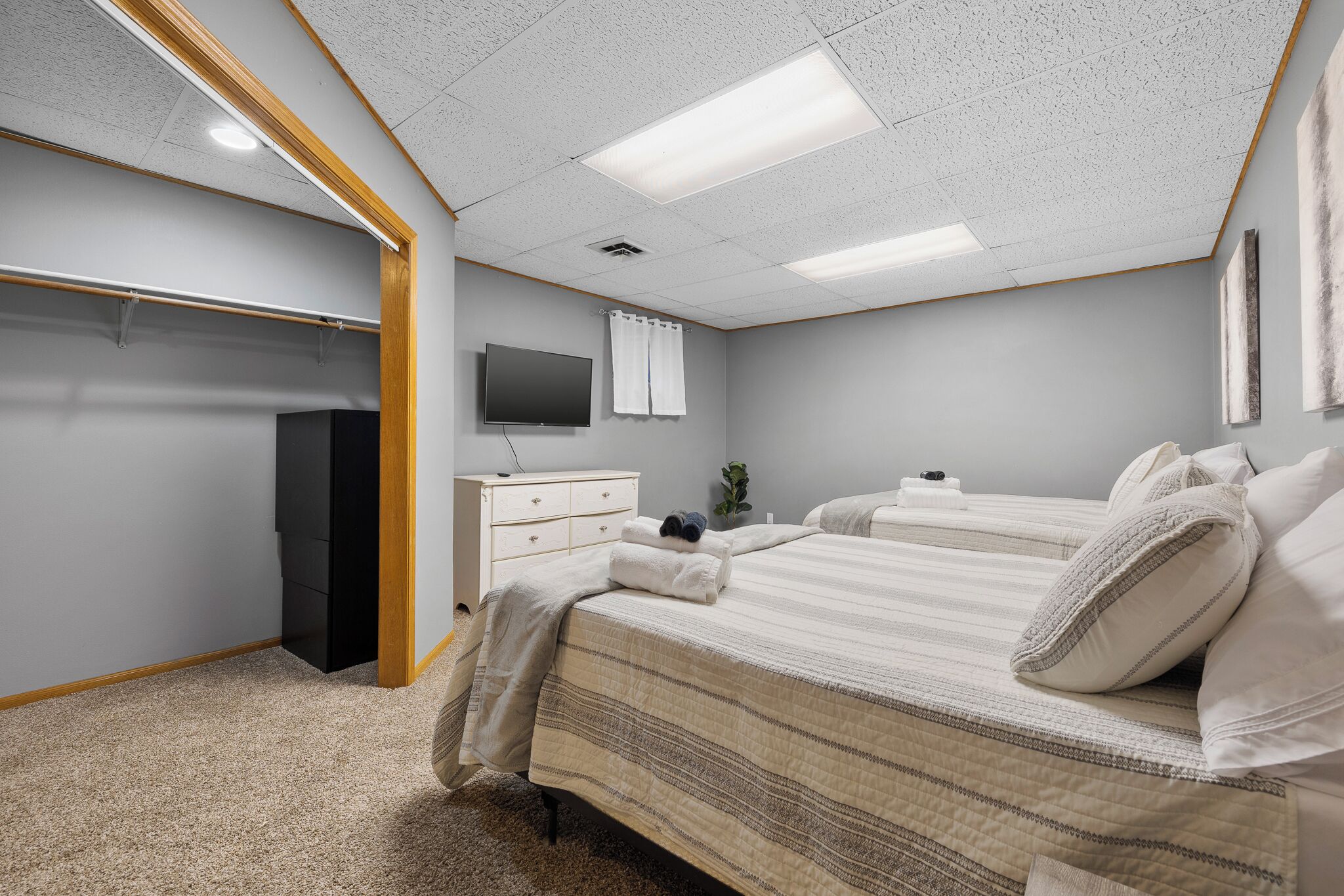 A bedroom with two beds, a TV, a dresser, and a closet.