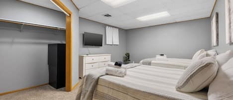 A bedroom with two beds, a TV, a dresser, and a closet.