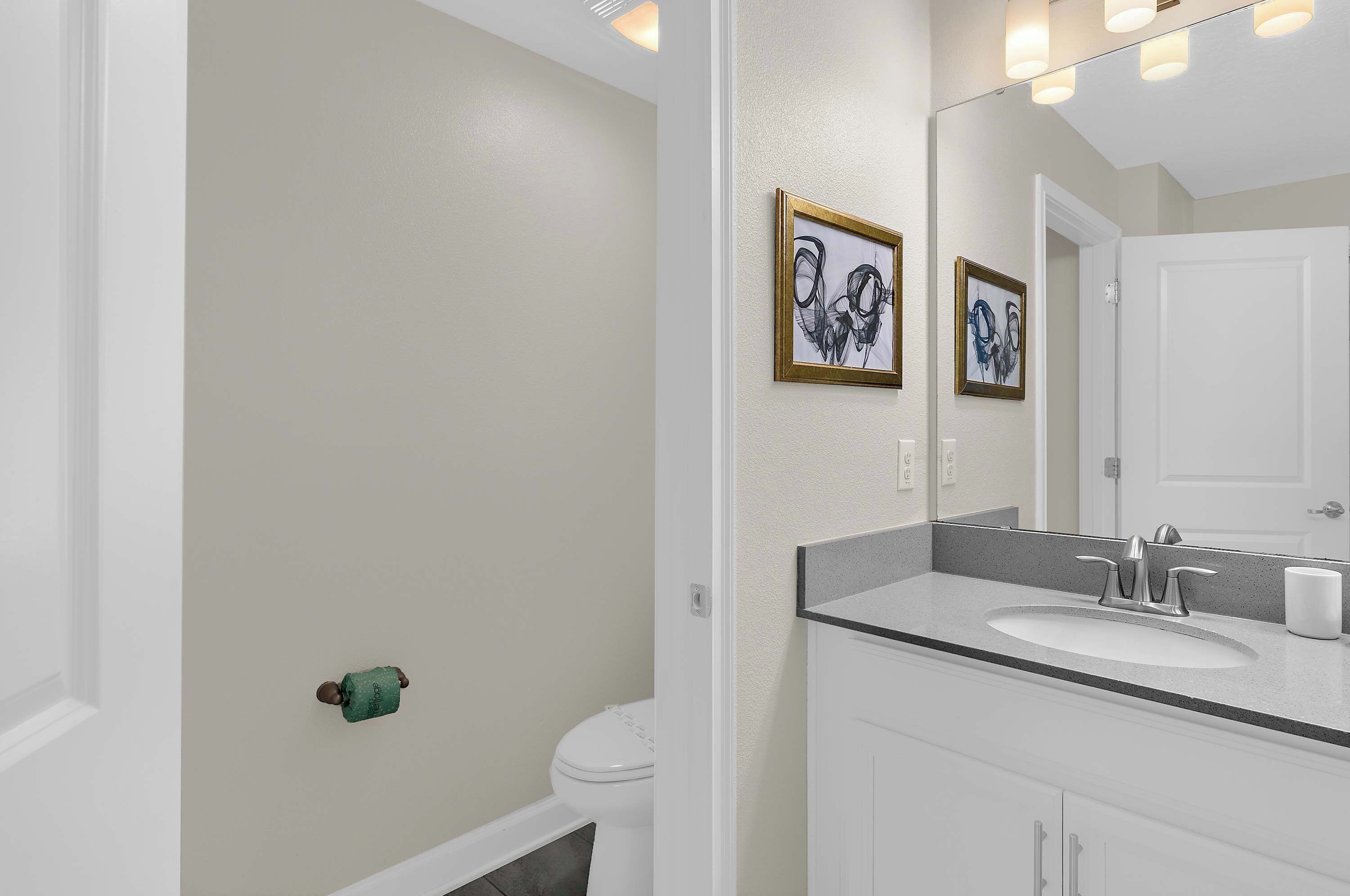 Ein Badezimmer mit einem weißen Waschbecken, einer Toilette und zwei gerahmten Kunstwerken an der Wand.