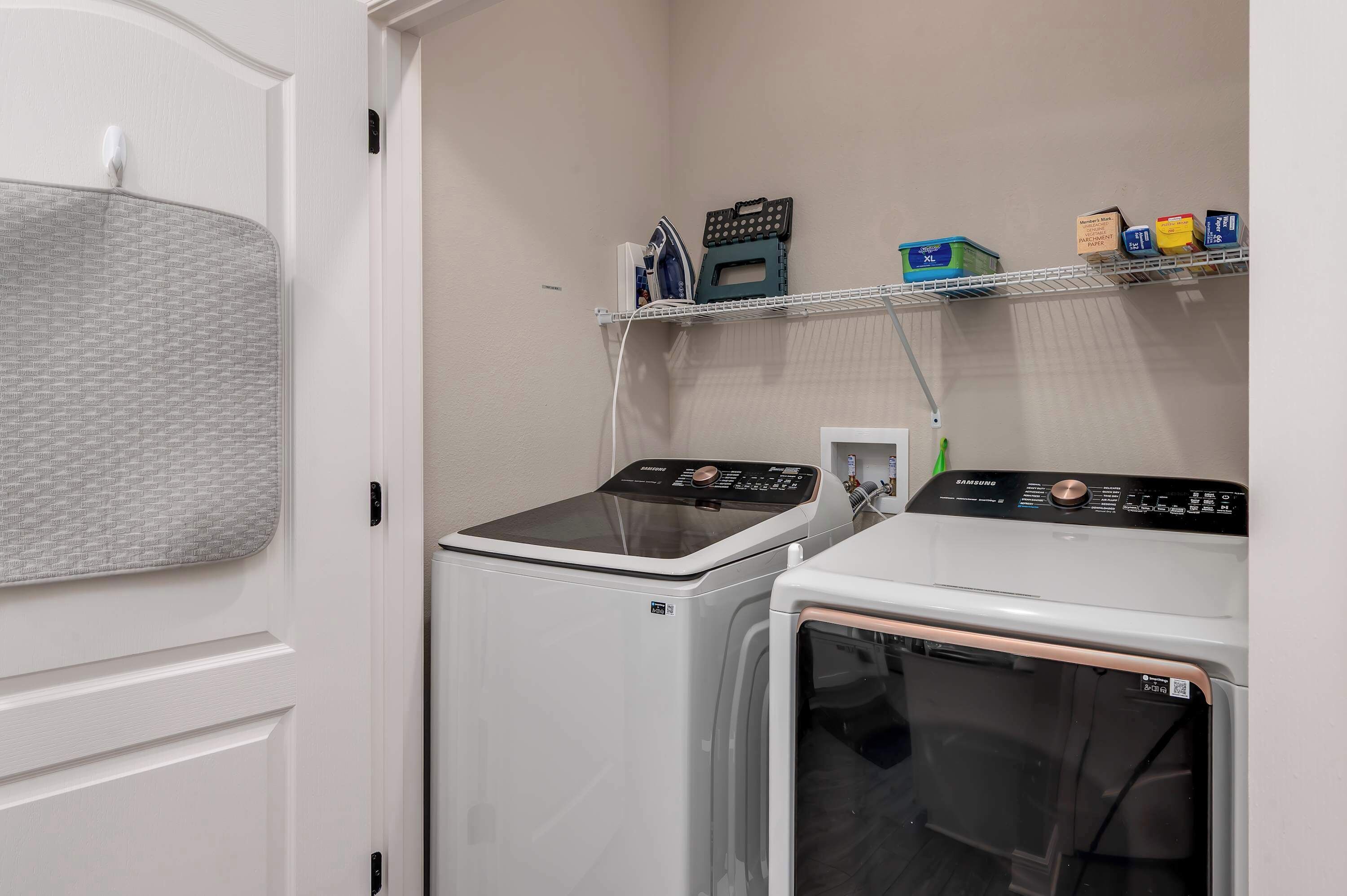 A laundry room with a washing machine, dryer, and shelves with laundry supplies.