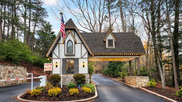 Een klein huis met een stenen muur, een Amerikaanse vlag en een oprit er naartoe.