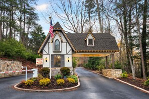 A small house with a stone wall, an American flag, and a driveway leading to it.