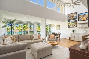 A spacious living area with a large sofa, a dining table, and a kitchen area. - Beachfront Penthouse with Private Terrace, Ocean & El Yunque Views – Casa Bacci (Río Grande)