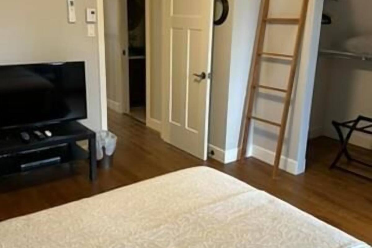 Een slaapkamer met een groot bed, een televisie, een deur en een kast.