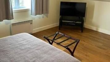 A bedroom with a bed, a television, and a window with curtains.