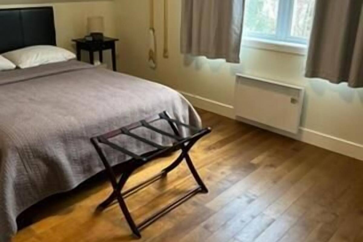 Een slaapkamer met een bed, nachtkastje, raam met gordijnen en een radiator.