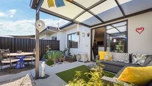 Um pátio moderno ao ar livre com área de refeições, assentos e um jardim.