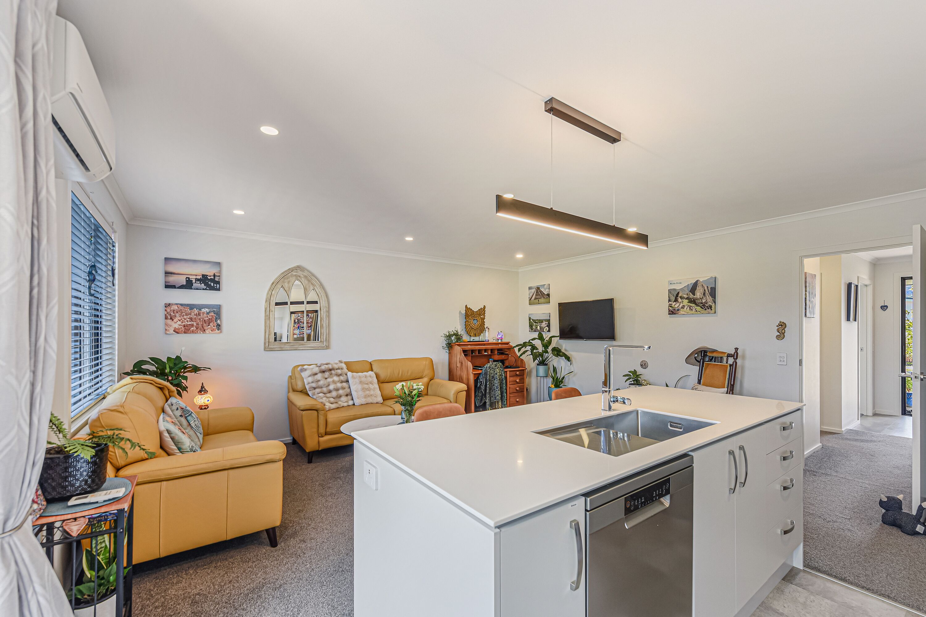 A modern kitchen with a built-in island, a dining area with a sofa, and a living room with a fireplace.