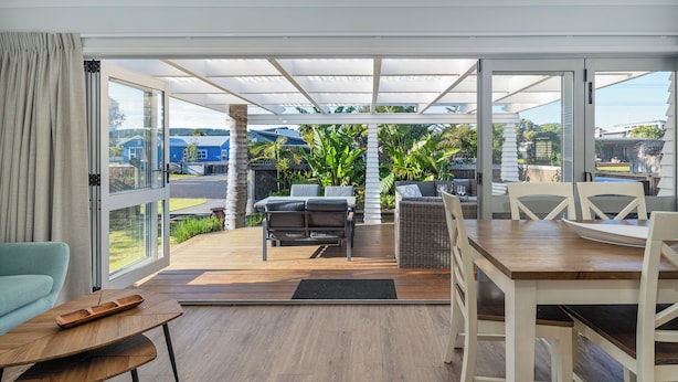 En moderne udendørs terrasse med spisebord, stole og sofa.