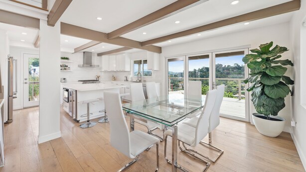 A modern kitchen with white cabinetry, a glass dining table, and a large potted plant. - Silver Lake Hills Home with Views • Patio • Near Sunset Junction (Los Angeles)