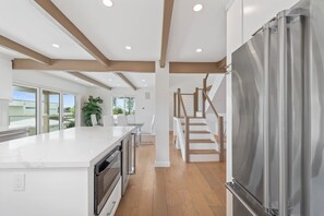 Una cocina moderna con una isla grande, horno empotrado y refrigerador de acero inoxidable.