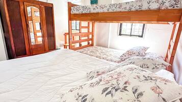 A bunk bed with floral bedding, a wooden wardrobe, and a television on the wall.