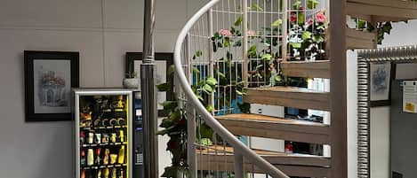 A spiral staircase with metal railings, a vending machine, and potted plants.