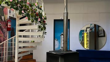 A spiral staircase with a fire extinguisher, a black heater, and a blue sofa.