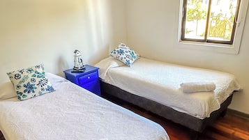Una habitación con dos camas, una ventana y una mesita de noche azul.
