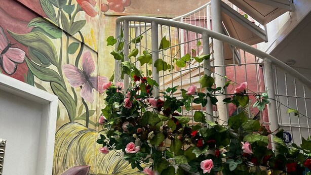 En spiraltrappa med en väggmålning som föreställer blommor och ett kvinnligt ansikte.