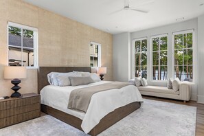 A bedroom with a large bed, a sofa, and a view of trees through large windows. - Masters Week Reynolds Lake Oconee Luxury Lake Property in Richland Point Pool&HT (Greensboro)
