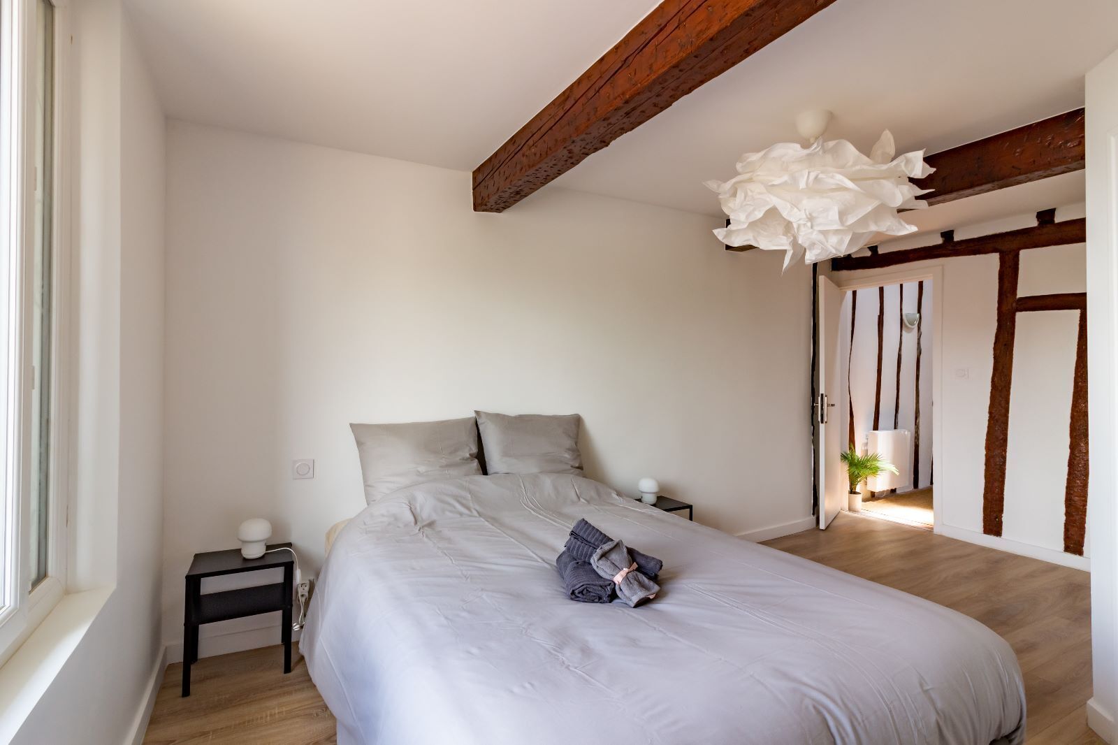 Une chambre à coucher comprenant un lit, des tables de chevet, un luminaire suspendu et une porte avec un cadre en bois.