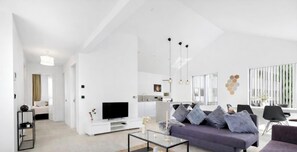 Ein modernes Wohnzimmer mit Sofa, Couchtisch und Fernseher.