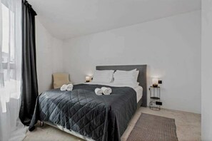 Ein modernes Schlafzimmer mit Bett, Nachttischlampen und Blick ins Freie.
