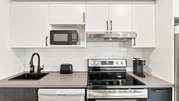 A modern kitchen with white cabinetry, a built-in microwave, a stainless steel range hood, a toaster, an oven, and a dishwasher.