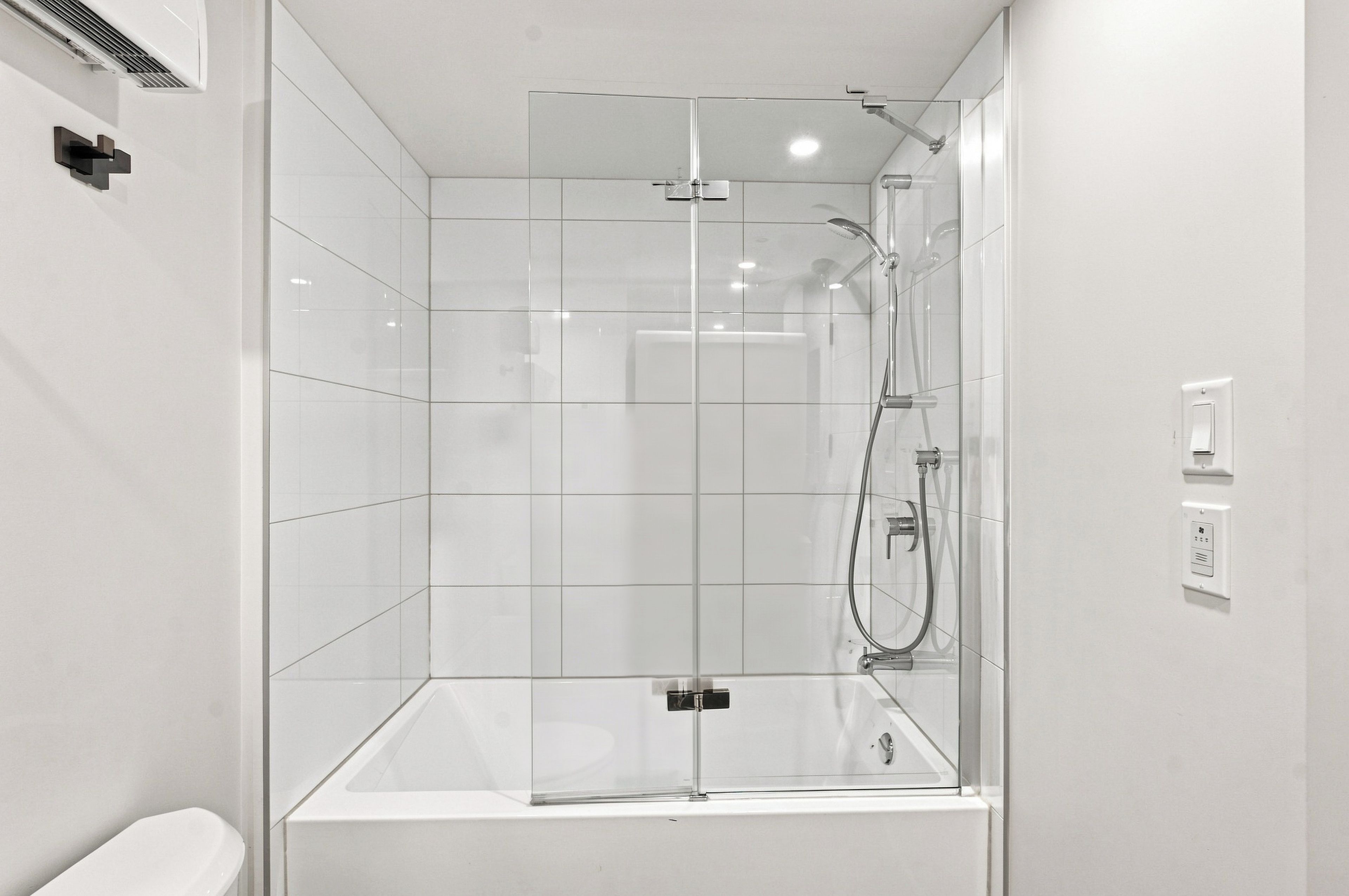 Un baño moderno con ducha de vidrio, una bañera blanca y un inodoro.
