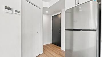 Una cocina moderna con refrigerador de acero inoxidable, armarios blancos y piso de madera.
