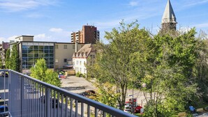 A view of a town with various buildings, including a church with a spire, and a modern building with large windows. - Appart'hôtel Viveo - Par Aneyro (Québec)