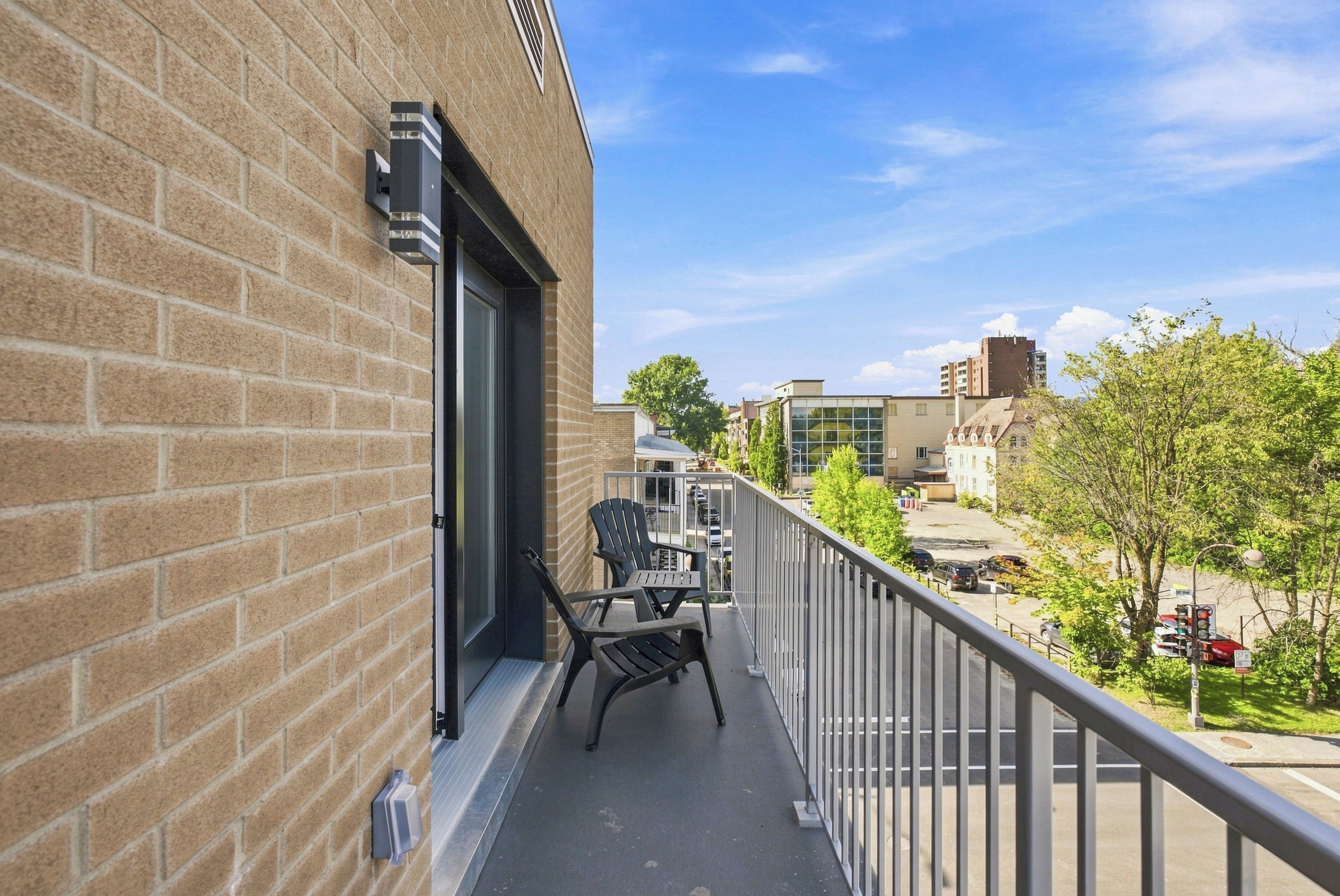 Ein Balkon mit Blick auf eine Stadtlandschaft, mit Backsteinmauern und einem Metallgeländer.