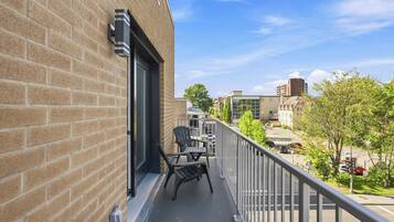 Ein Balkon mit Blick auf eine Stadtlandschaft, mit Backsteinmauern und einem Metallgeländer.