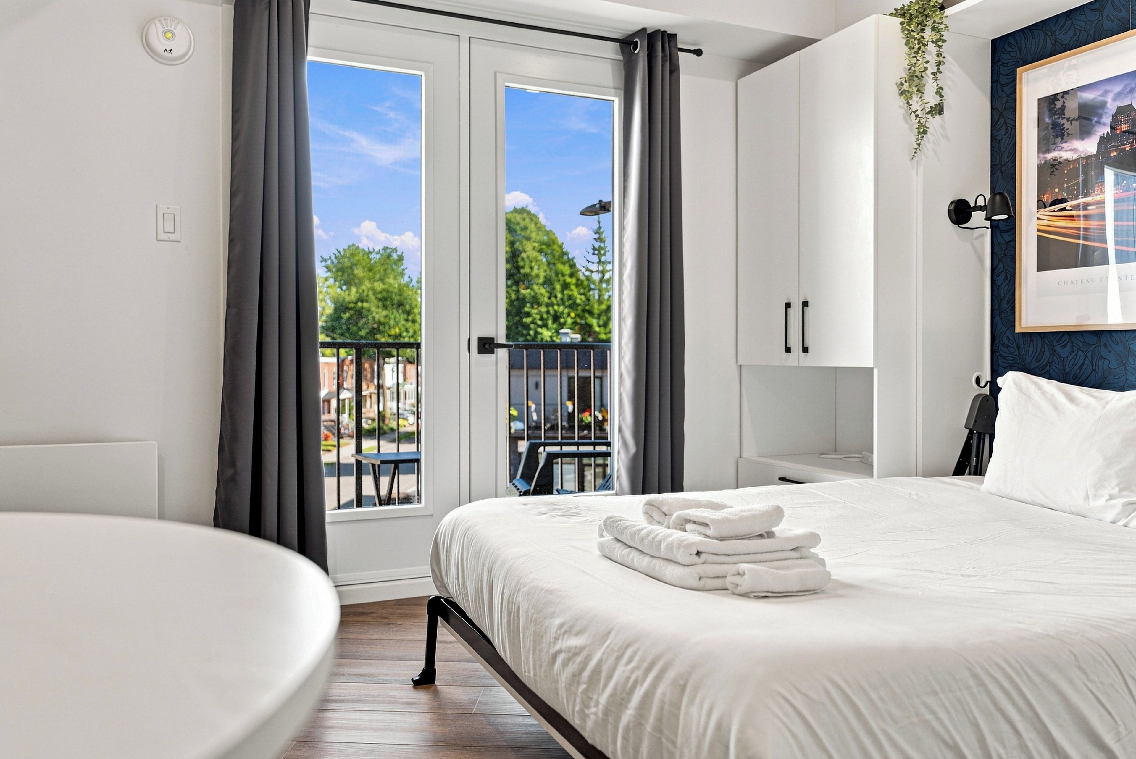 Una habitación de hotel con cama, una silla, un balcón y vistas al exterior.